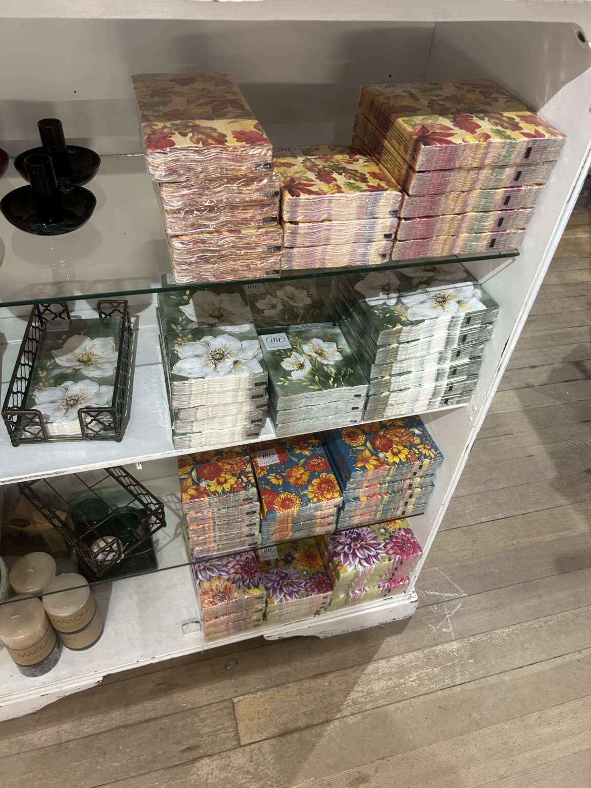 Shelving unit stocked with colorful decorative paper napkins, tissue boxes, and floral gift sets
