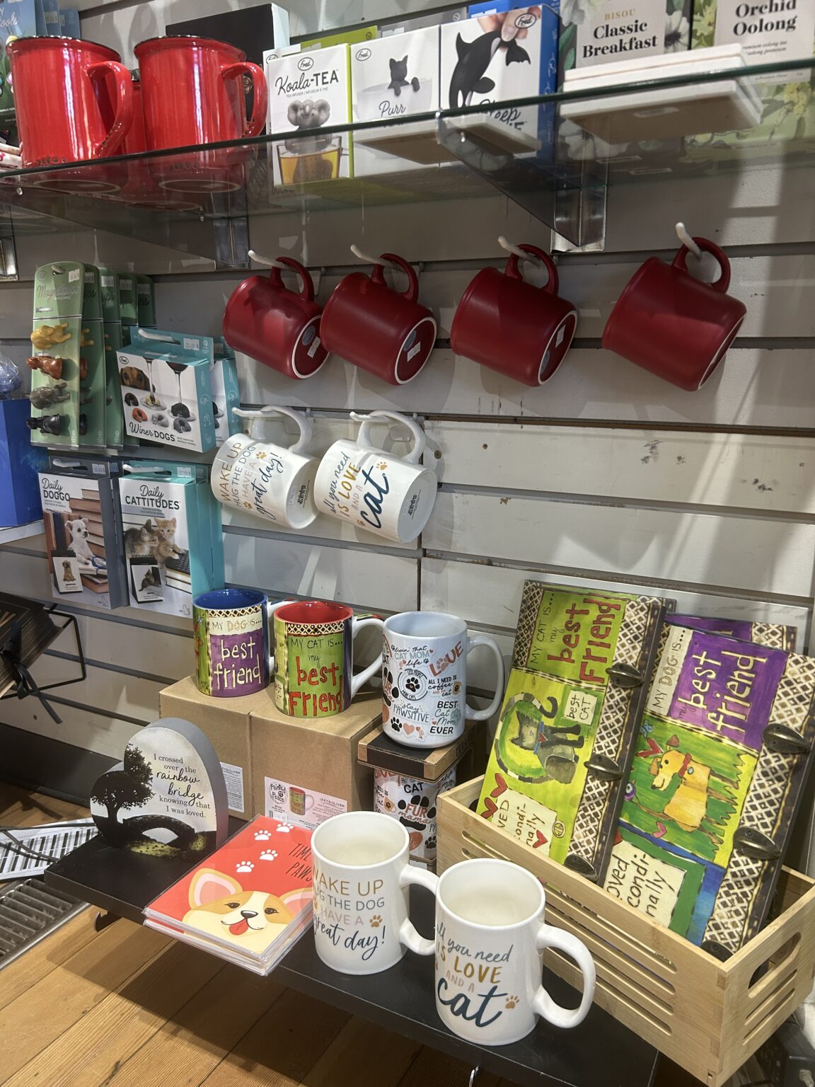 Display shelves featuring red mugs, greeting cards, and patterned kitchen organizers