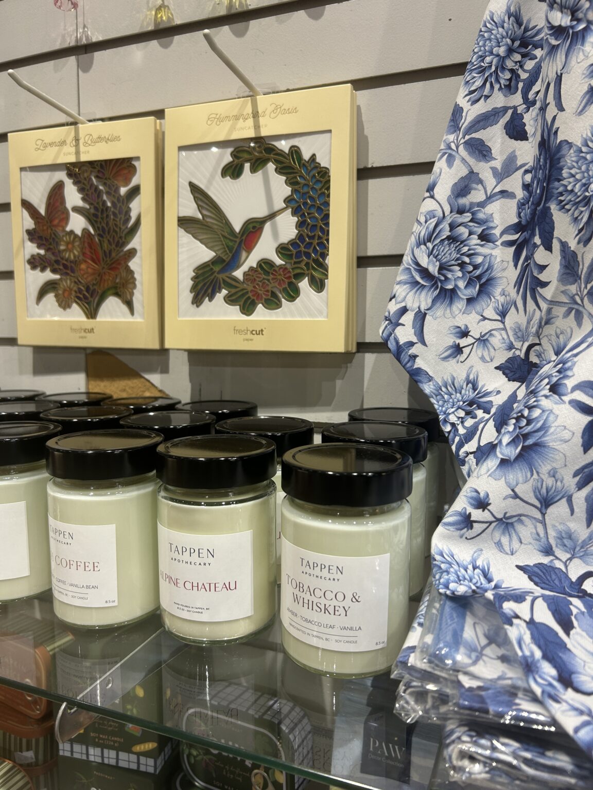 White tea towels featuring green plant illustrations paired with amber glass jar candles.